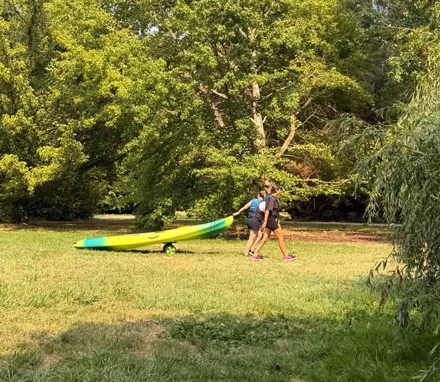 Deux personnes tirant un kayak à travers le parc vers la rivière
